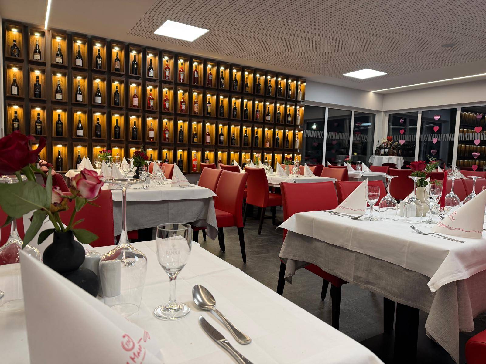 Gastraum mit Weinregal und weiß eingedeckten Tischen